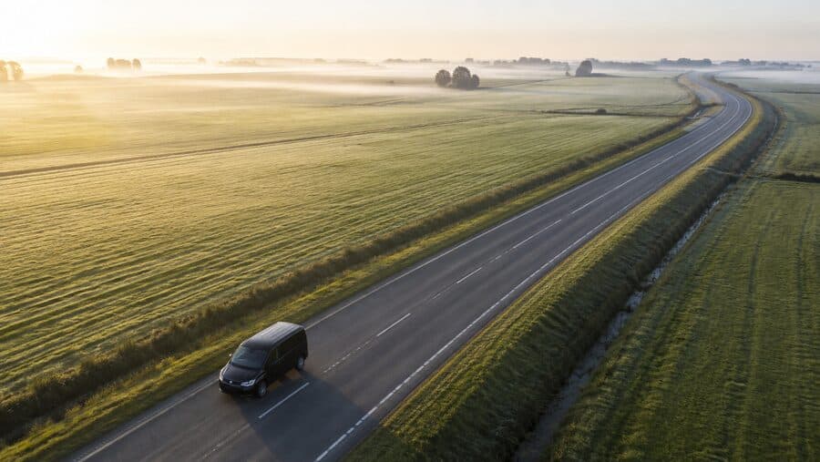 Transporter auf einer Landstraße bei Sonnenaufgang